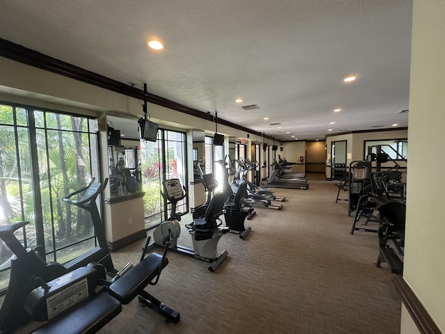 exercise room featuring recessed lighting, visible vents, ornamental molding, a textured ceiling, and baseboards