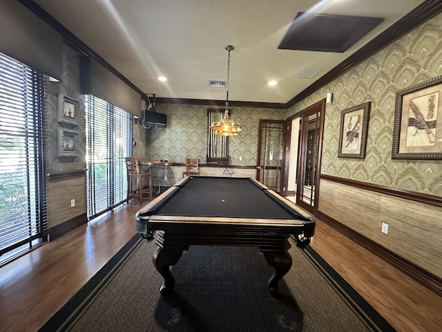 game room featuring dark wood-style floors, ornamental molding, visible vents, and wallpapered walls