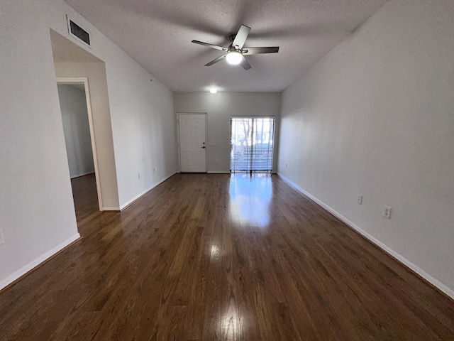 spare room with ceiling fan, a textured ceiling, visible vents, baseboards, and dark wood-style floors