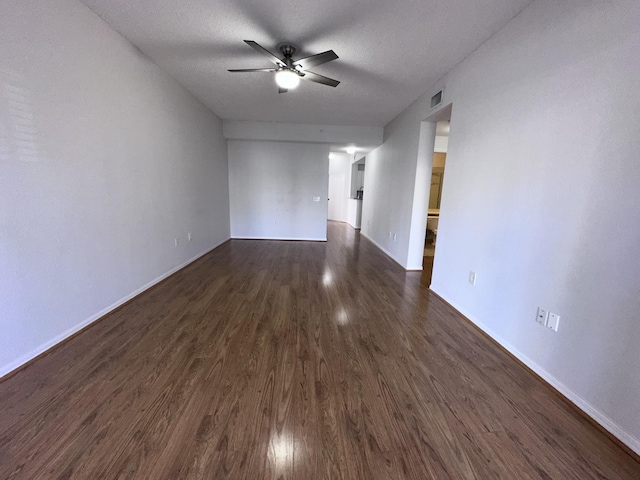 unfurnished living room featuring a textured ceiling, visible vents, a ceiling fan, baseboards, and dark wood-style floors