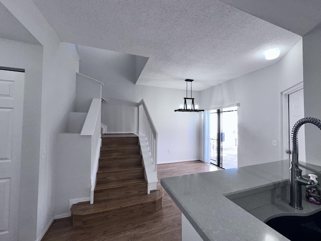 interior space with pendant lighting, dark wood finished floors, a barn door, a sink, and a textured ceiling