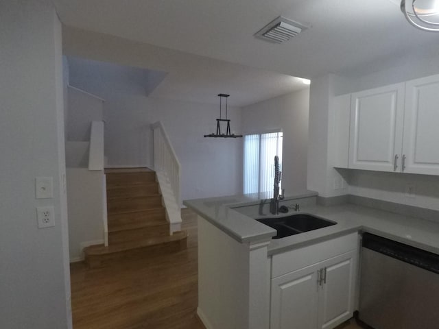 kitchen featuring visible vents, white cabinets, a sink, dishwasher, and a peninsula