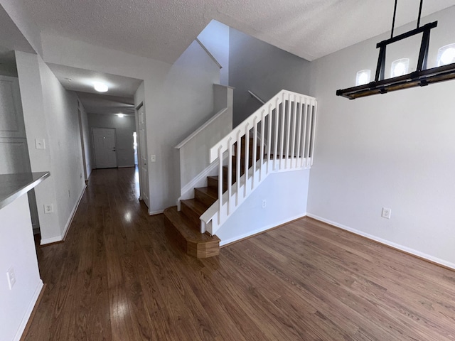 stairway featuring a textured ceiling, baseboards, and wood finished floors