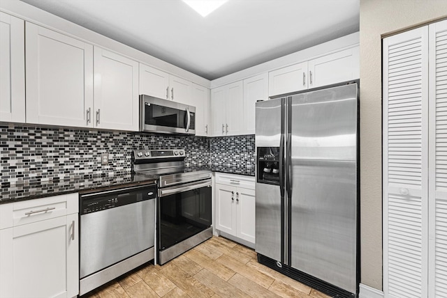 kitchen with appliances with stainless steel finishes, dark countertops, white cabinets, and tasteful backsplash