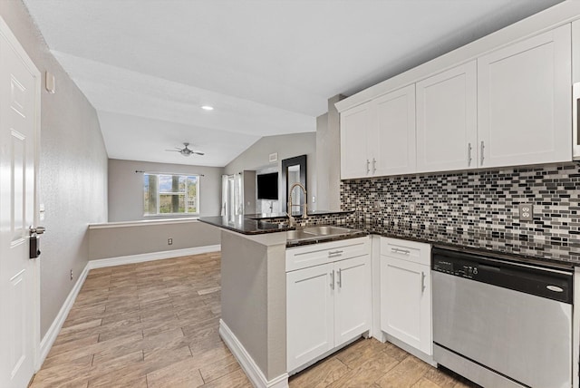 kitchen with tasteful backsplash, lofted ceiling, a peninsula, stainless steel dishwasher, and a sink