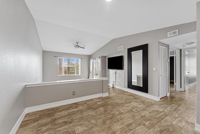 unfurnished living room featuring baseboards, visible vents, vaulted ceiling, and a ceiling fan