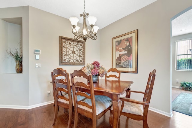 dining area featuring wood finished floors, baseboards, and a chandelier