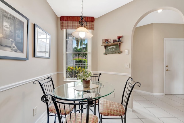 dining room with light tile patterned flooring, baseboards, and arched walkways