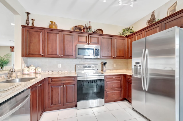 kitchen with decorative backsplash, light stone countertops, appliances with stainless steel finishes, and a sink