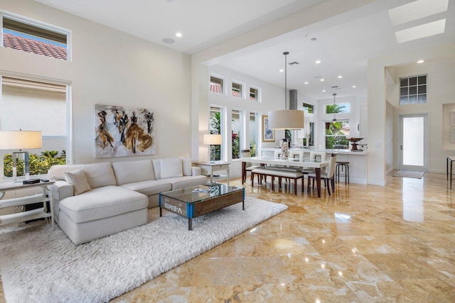 living room with recessed lighting, marble finish floor, a towering ceiling, and baseboards