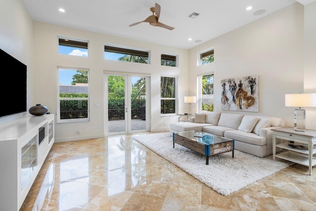 living area featuring french doors, visible vents, a high ceiling, and a healthy amount of sunlight