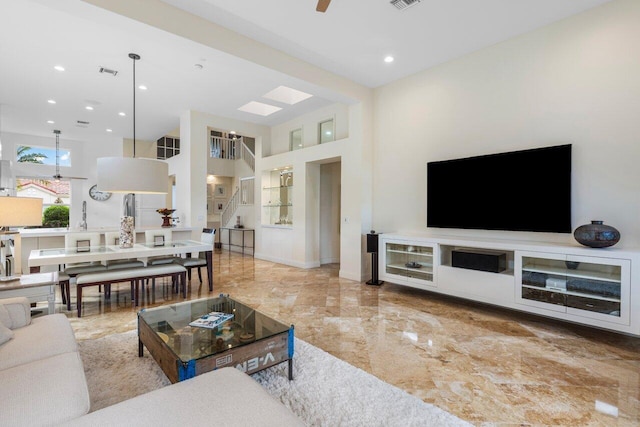 living room with a ceiling fan, marble finish floor, visible vents, and baseboards