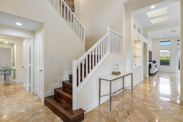 stairs with marble finish floor, a high ceiling, baseboards, and recessed lighting