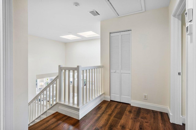 hallway with baseboards, visible vents, an upstairs landing, and wood finished floors