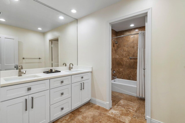 full bath with double vanity, baseboards, a sink, and shower / tub combo with curtain