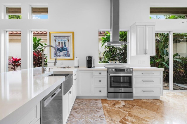 kitchen featuring island range hood, a sink, white cabinets, light countertops, and appliances with stainless steel finishes