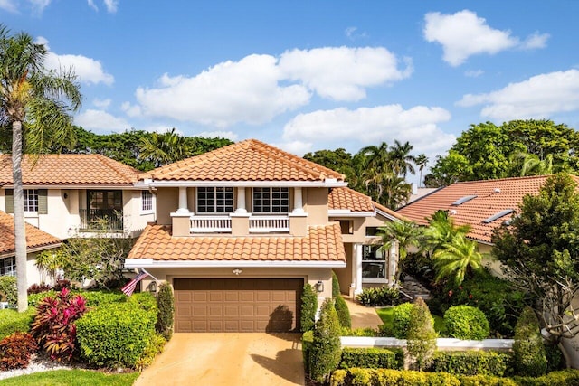 mediterranean / spanish house with a balcony, driveway, a tiled roof, and stucco siding