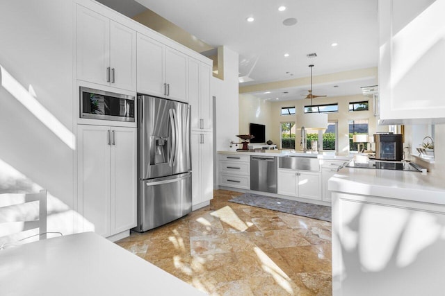 kitchen with white cabinets, a peninsula, stainless steel appliances, light countertops, and a sink