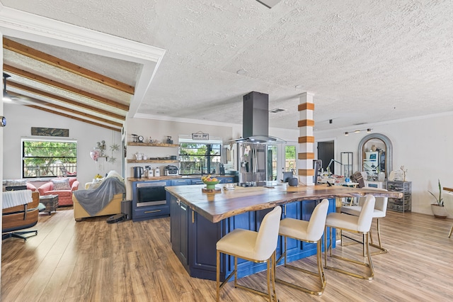 kitchen featuring light wood-type flooring, blue cabinetry, island exhaust hood, and wooden counters