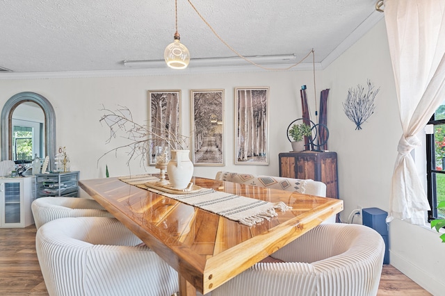 dining area with a textured ceiling, wood finished floors, and crown molding