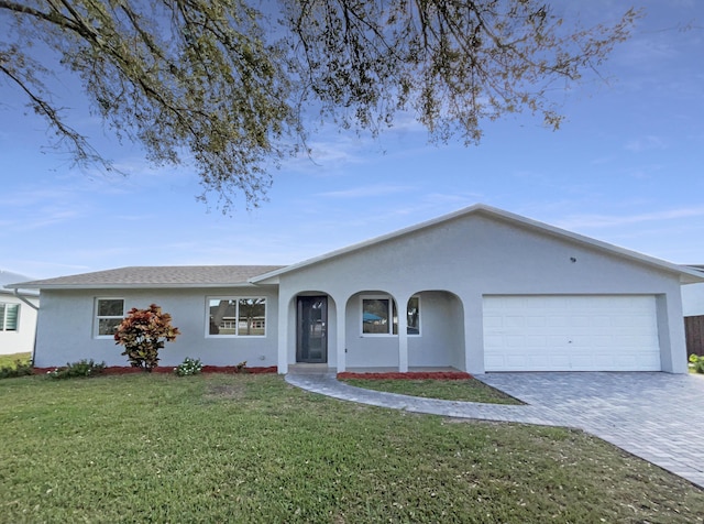 single story home with a front yard, decorative driveway, an attached garage, and stucco siding