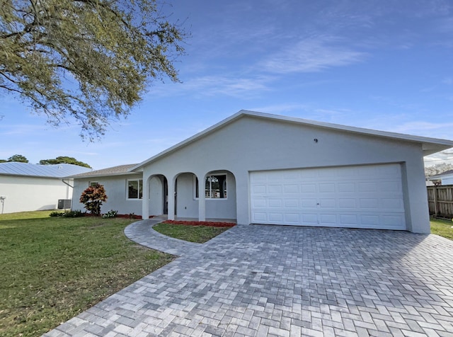 ranch-style home featuring a front lawn, decorative driveway, and stucco siding