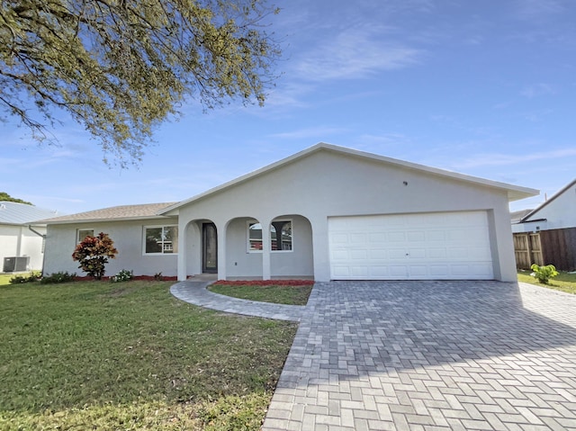 single story home with decorative driveway, a front yard, central AC, and stucco siding