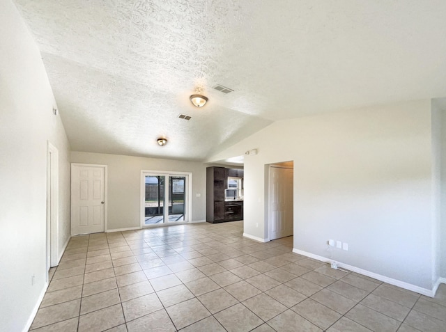 spare room with lofted ceiling, light tile patterned floors, a textured ceiling, visible vents, and baseboards