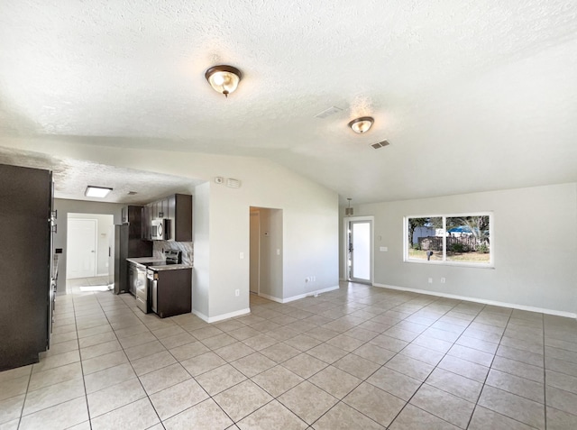 unfurnished living room with lofted ceiling, light tile patterned floors, baseboards, and visible vents