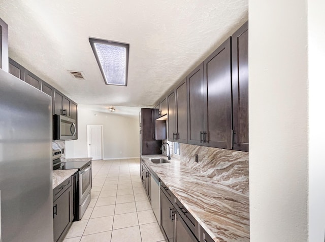 kitchen featuring light tile patterned floors, a sink, visible vents, dark brown cabinets, and appliances with stainless steel finishes