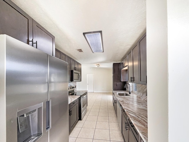 kitchen with light tile patterned floors, visible vents, appliances with stainless steel finishes, a sink, and dark brown cabinets