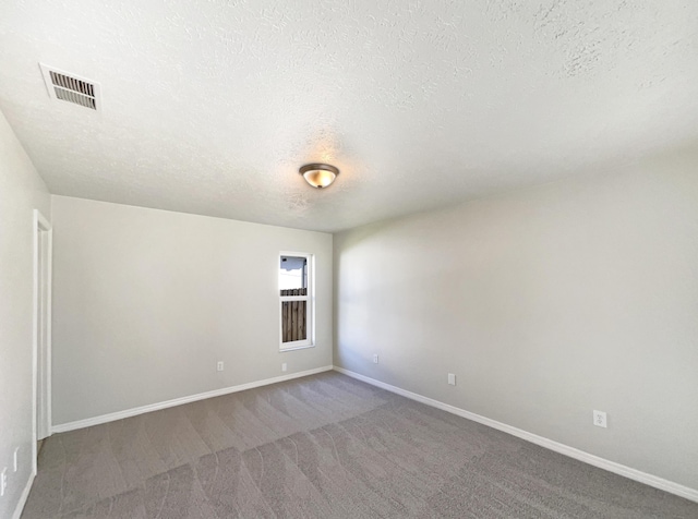 empty room featuring carpet floors, baseboards, visible vents, and a textured ceiling