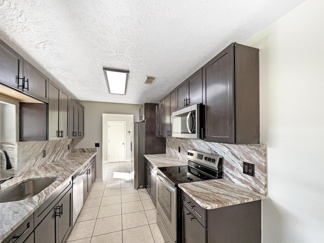 kitchen with light tile patterned floors, visible vents, decorative backsplash, appliances with stainless steel finishes, and light stone countertops