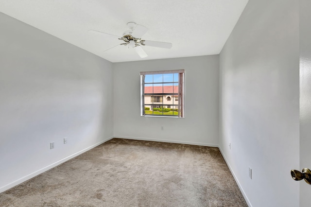 carpeted empty room with baseboards and a ceiling fan