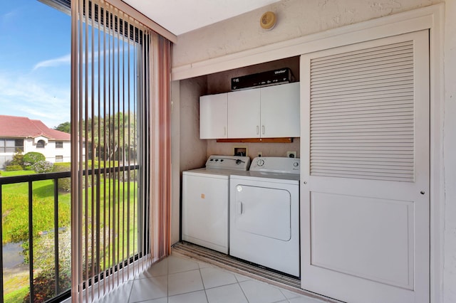 laundry room featuring light tile patterned flooring, washing machine and clothes dryer, and cabinet space