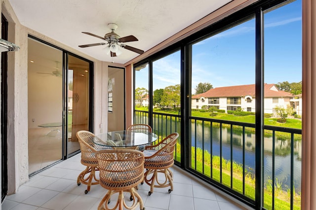 sunroom / solarium with a water view, a ceiling fan, and a wealth of natural light