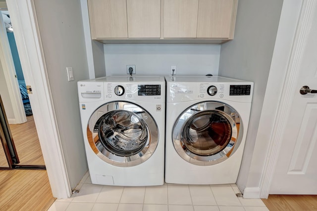 washroom featuring washing machine and dryer, cabinet space, and light tile patterned floors