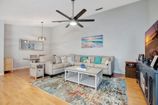 living area featuring visible vents, baseboards, ceiling fan, vaulted ceiling, and light wood-style floors