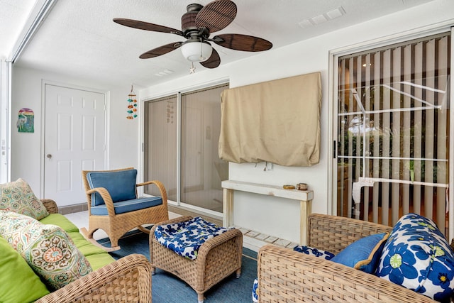 living area with visible vents, ceiling fan, and a textured ceiling