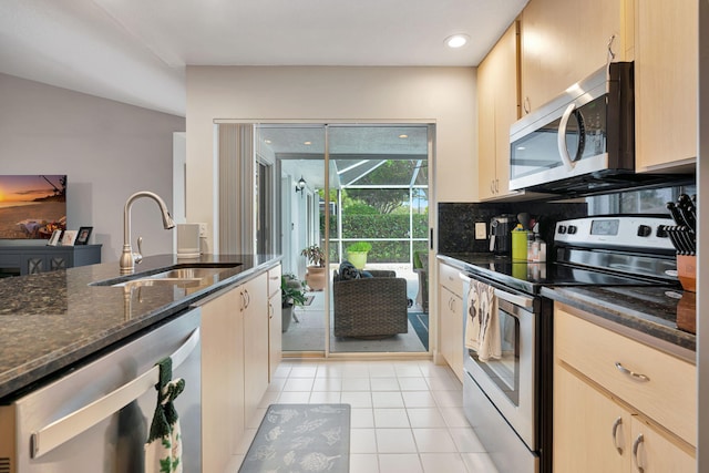 kitchen with stainless steel appliances, light brown cabinetry, light tile patterned flooring, and a sink