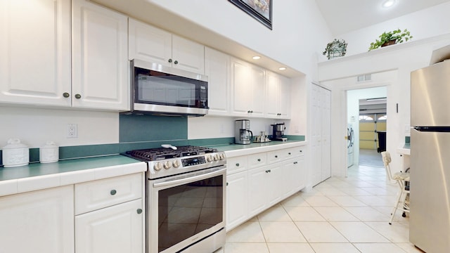 kitchen with appliances with stainless steel finishes, light countertops, white cabinetry, and visible vents