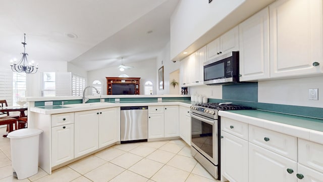 kitchen featuring vaulted ceiling, a peninsula, appliances with stainless steel finishes, and white cabinetry