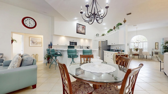 dining space with a chandelier, high vaulted ceiling, light tile patterned floors, and visible vents