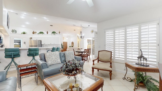 living room with light tile patterned flooring, baseboards, and ceiling fan with notable chandelier