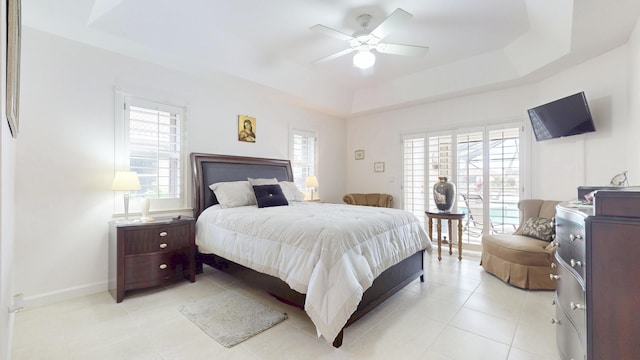 bedroom featuring baseboards, a tray ceiling, and a ceiling fan