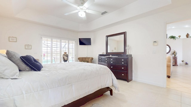 bedroom with light tile patterned floors, a raised ceiling, visible vents, a ceiling fan, and baseboards