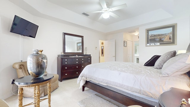 bedroom featuring light tile patterned floors, a raised ceiling, visible vents, ensuite bathroom, and a ceiling fan