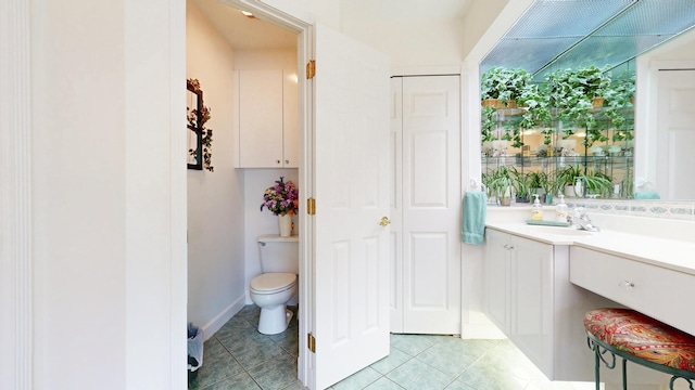 bathroom with toilet, vanity, a closet, and tile patterned floors