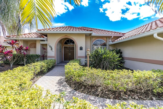 entrance to property featuring a tile roof and stucco siding