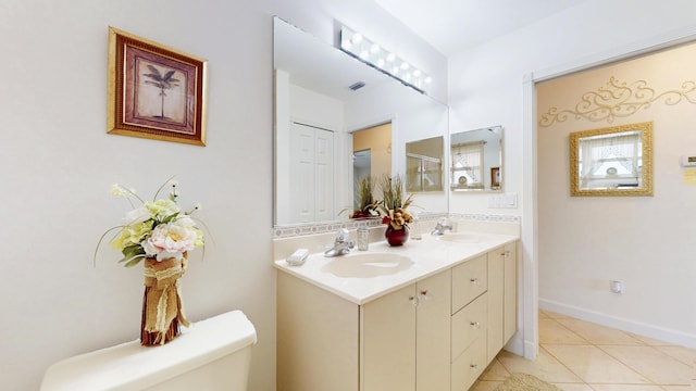 bathroom with toilet, a sink, visible vents, tile patterned floors, and double vanity
